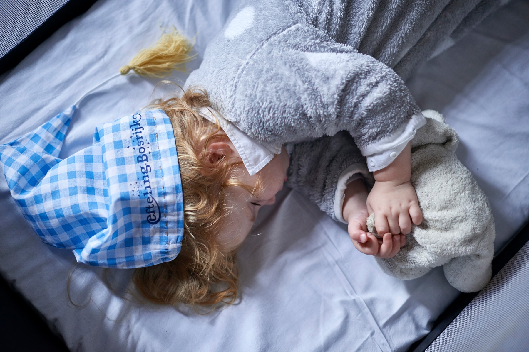 Slapend kind met slaapmuts van Efteling Bosrijk op.