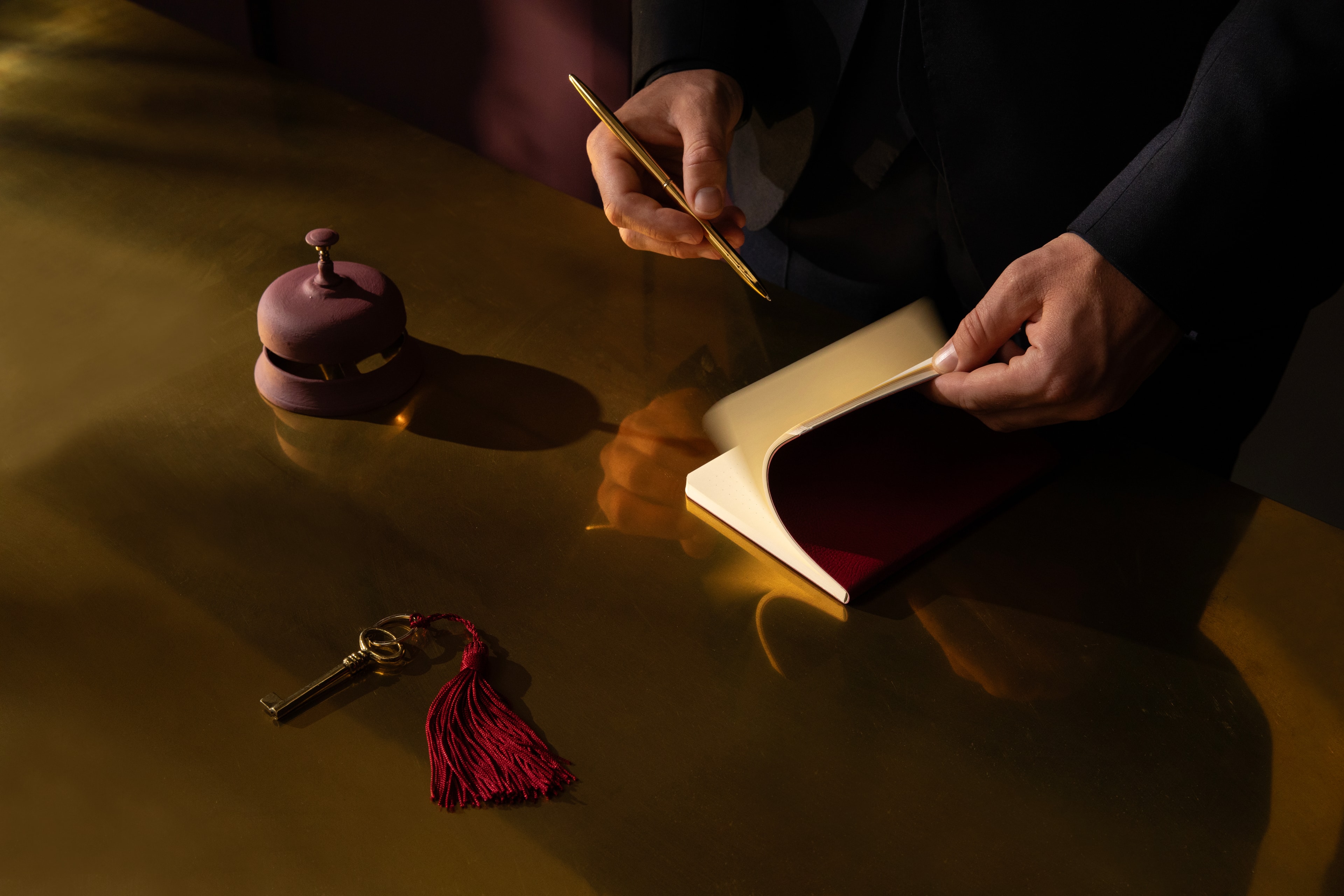 Hand medewerker met een notitieboekje, receptiebel en sleutel.