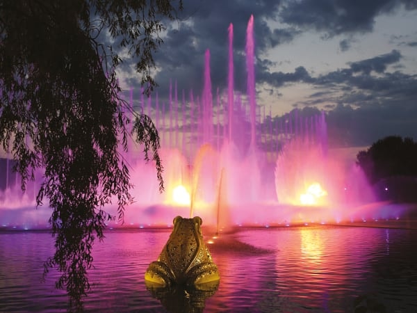 Spectaculaire roze en gele lichtshow bij Aquanura in de Efteling tijdens een zomerse schemering.