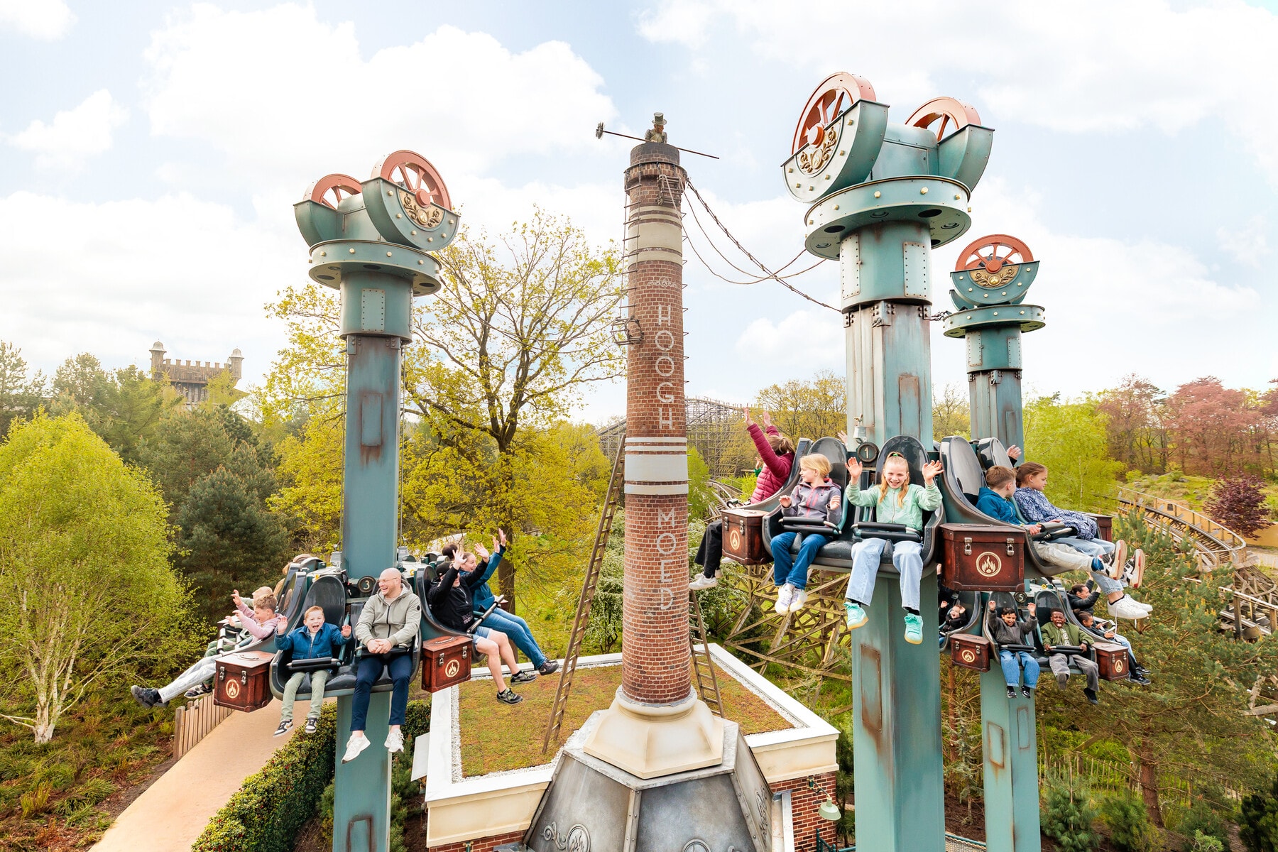 Gasten zweven in stoeltjes rond de torens van attractie Hooghmoed in Efteling Park.