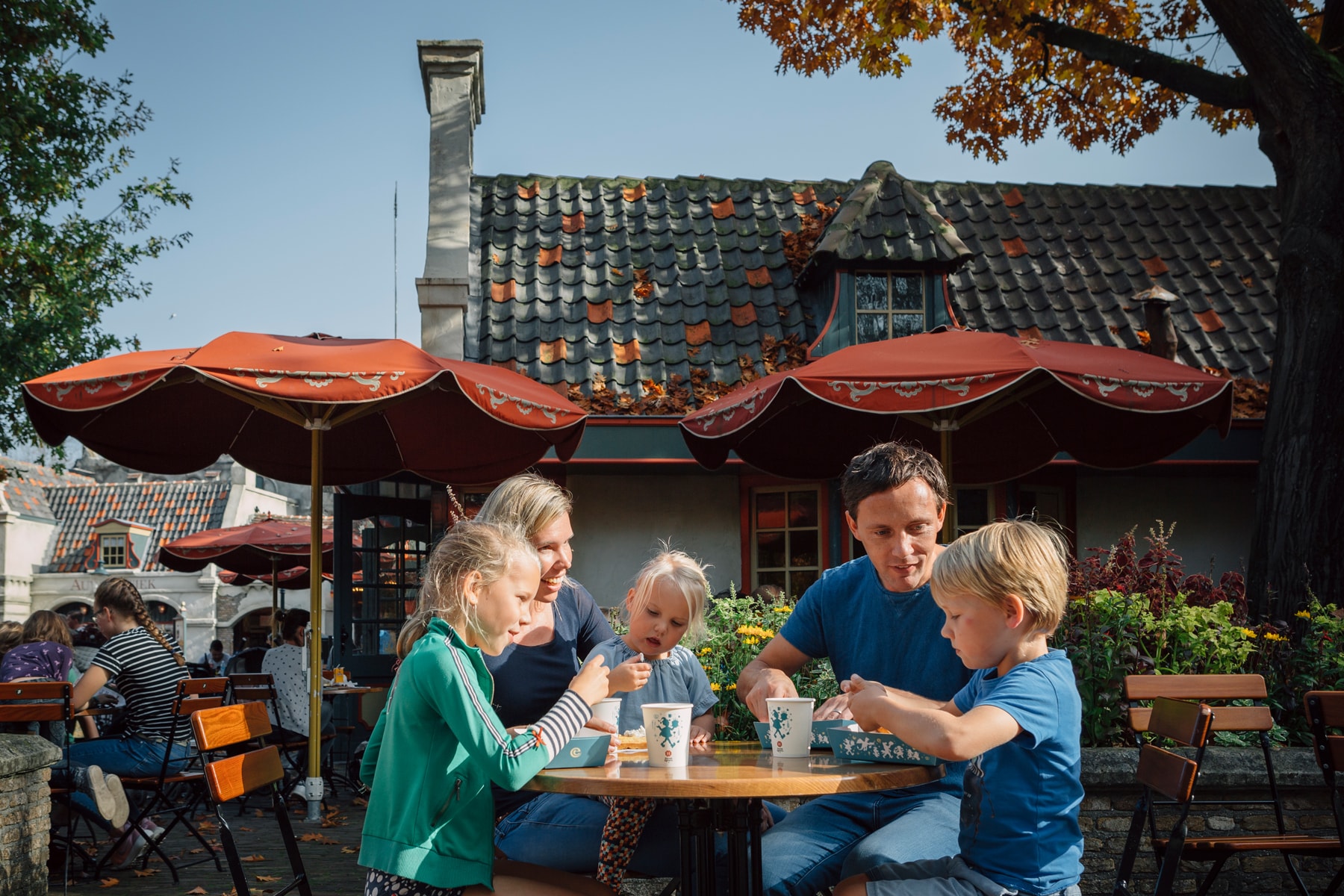 Twee volwassenen en drie kinderen genieten van drankjes en iets lekkers op het terras van Den Suykerbuyk in Efteling Park.