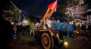 Efteling-Charaktere Max und Moritz sitzen auf einem bunten Wagen mit einer großen Feuerwerksrakete.