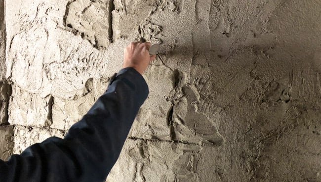 De vestingmuren van het slot worden met de hand bewerkt. Met een schraper krijgen de ‘stenen’ vorm. Later worden ze in de juiste kleur geschilderd.