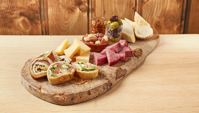 De hartige borrelplank van Polles Keuken met wraps, kaas, salami, tomatensalsa, stokbrood, nootjes en olijven.