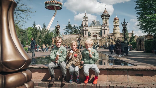 kindjes eten een softijsje op het hartenhof met symbolica op de achtergrond