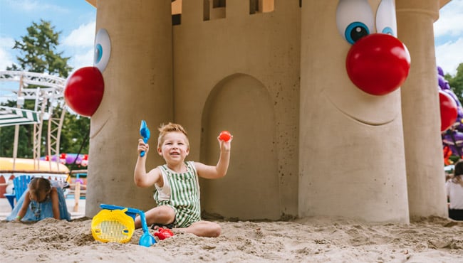 kindje speelt in het strand bij het zandkasteel op het zomerstrand