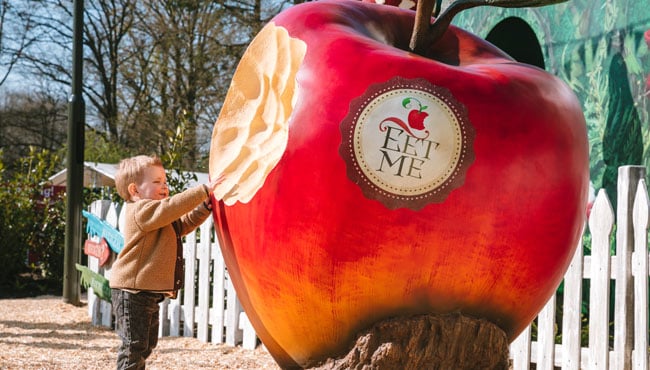 Jongentje probeert een hap te nemen uit een hele grote appel.