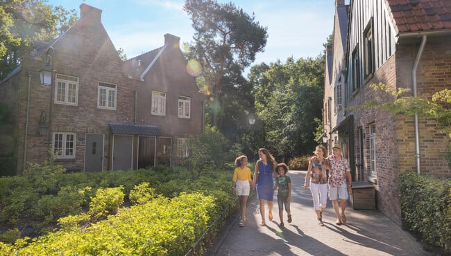 Familie lopend langs boshuizen in vakantiepark Efteling Bosrijk