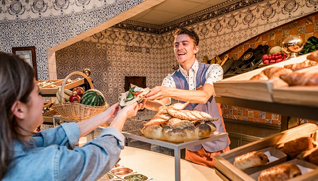 Efteling-medewerker overhandigt broodje aan een gast.