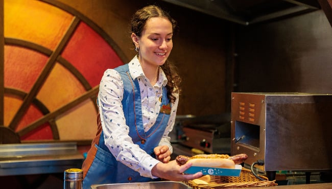 Efteling-medewerker geeft een broodje curryworst uit.
