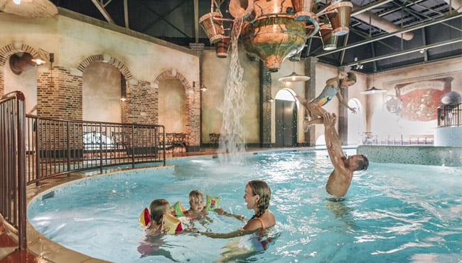 Gezin speelt in de overdekte waterspeelplaats - het Badhuys