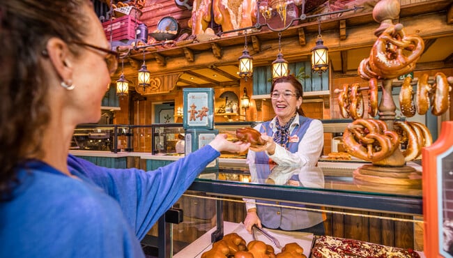 vrouw overhandigt gast een brood in Bäckerei Krümel
