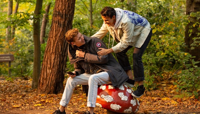 Twee jongens zittend op een paddenstoel in het Sprookjesbos van de Efteling.