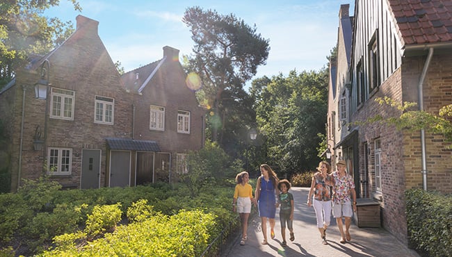 Gezin loopt over een plein met vakantiewoningen in Efteling Bosrijk.