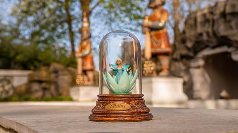 Een uniek souvenir voor Premium-abonnementhouders met een miniatuur van de Indische Waterlelies onder een glazen stolp, met op de achtergrond decoratieve wachters in het Sprookjesbos.