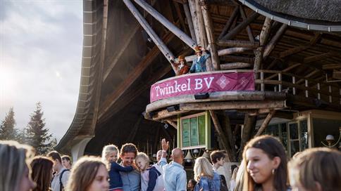 Groep bezoekers wordt welkom geheten door Sleuteliers bij de entree van de Efteling, onder een roze banner met bedrijfsnaam.