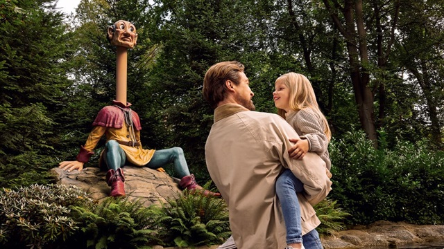 Man met een meisje in zijn armen in het Sprookjesbos bij het sprookje van De Zes Dienaren.