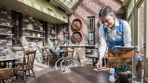 Medewerkster van Restaurant het Eethuys in Vakantiepark Efteling Bosrijk legt bestek op een tafel